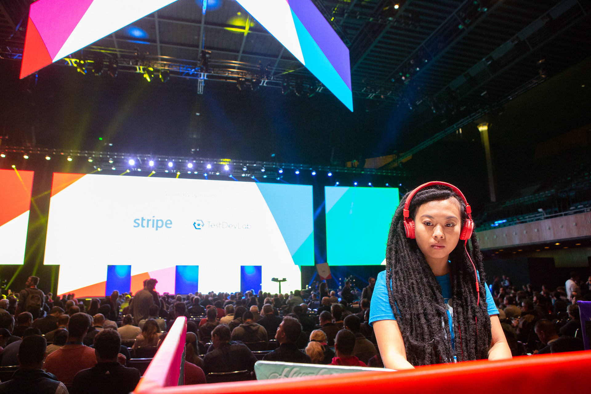 Attendee wearing red headphones at Stripe developer conference with colorful stage in background